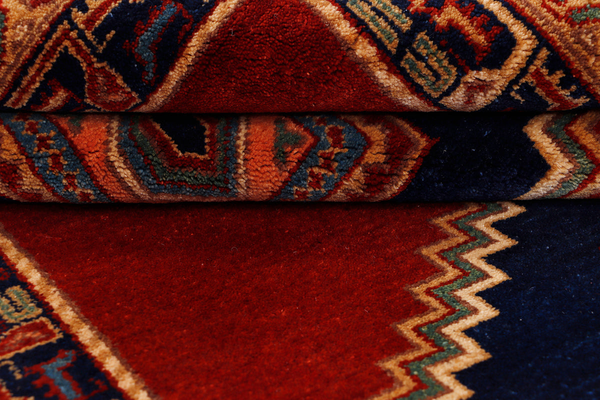 Red rug detail with zigzag border and dark blue geometric accents