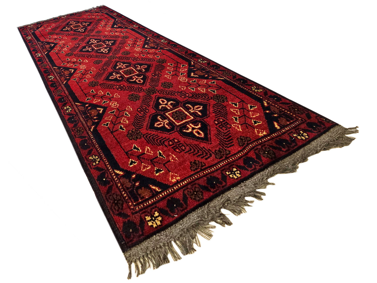 Red patterned runner rug with central medallion design and fringed corners