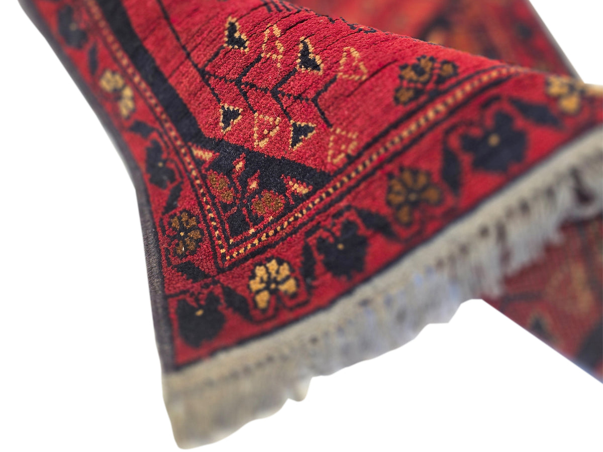 Diagonal view of red geometric runner rug with decorative border and fringe trim