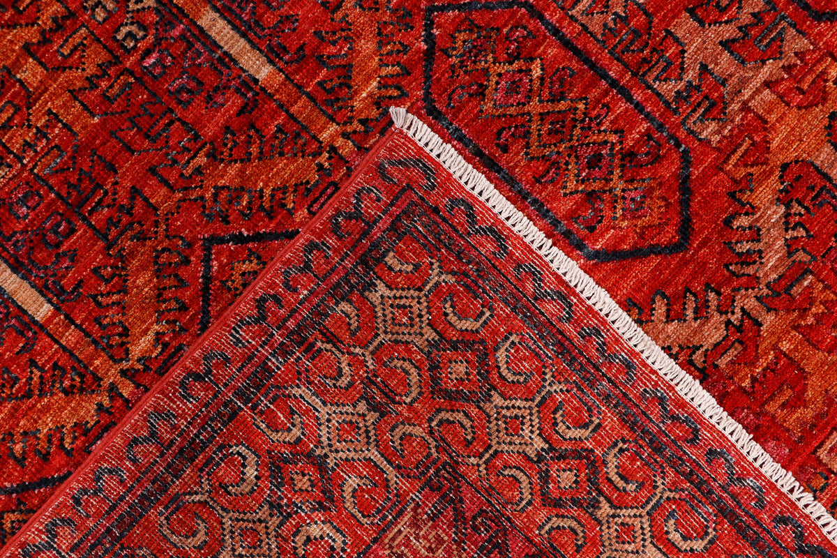 Red patterned rug corner with white fringe and ornate geometric motifs, close-up