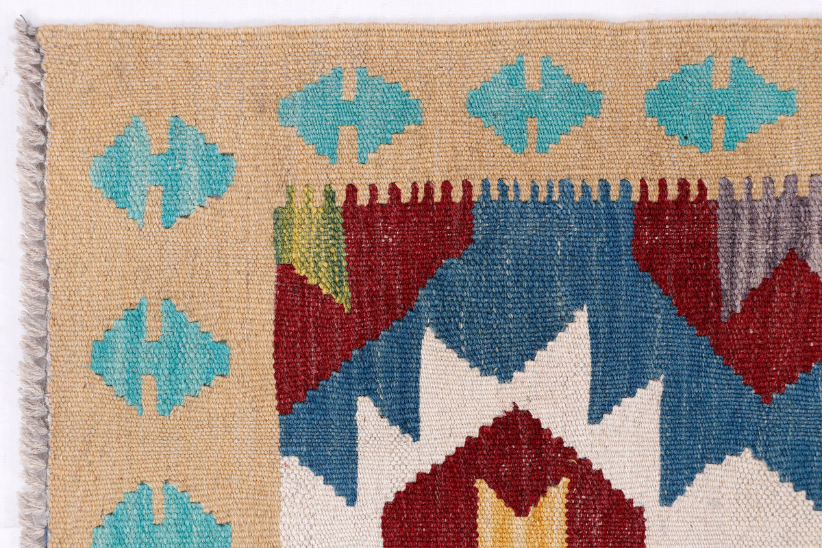 Kilim runner rug edge close-up with short fringe and blue, tan, red geometric motifs