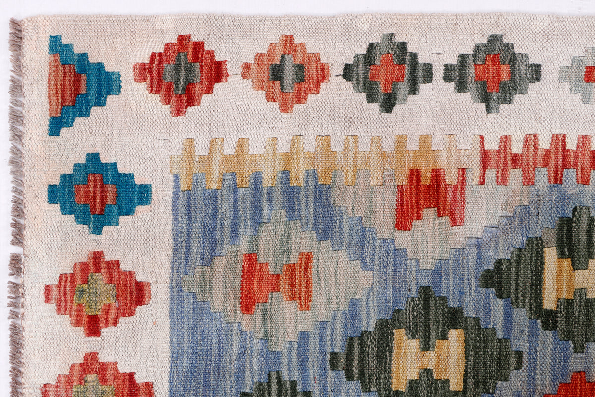 Kilim rug close-up showing red, blue, and black geometric crosses and borders