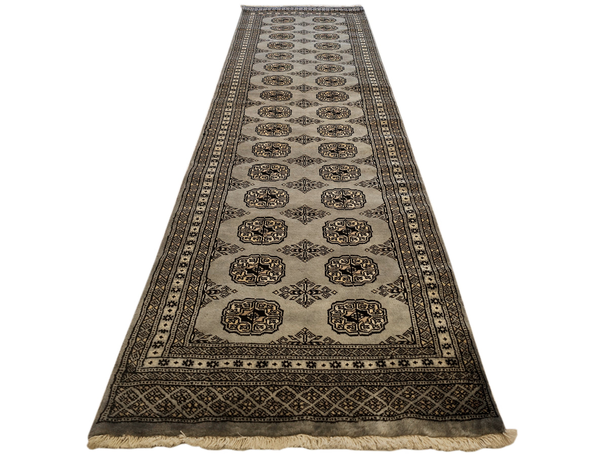 Bukhara-style area rug with dark border and repeating medallion motifs on light ground