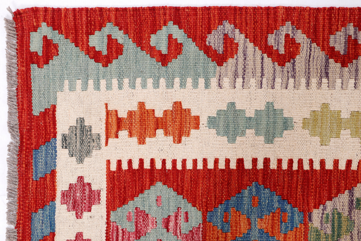 Kilim runner rug close-up with red, cream, blue, and green cross motif bands