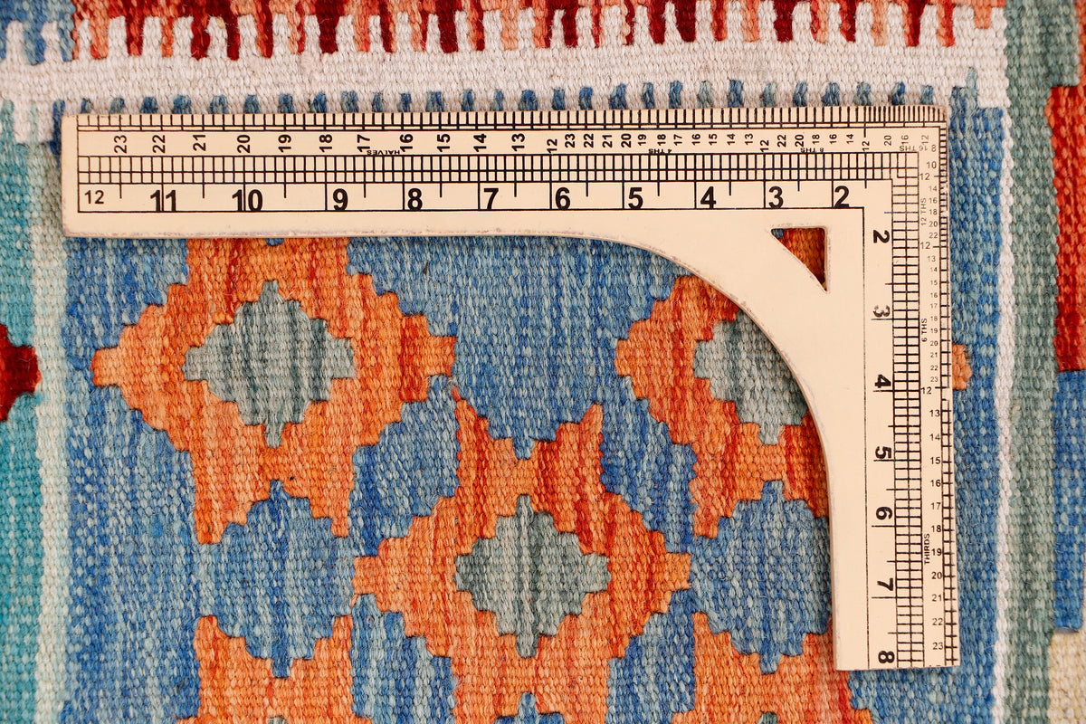 Blue and orange kilim rug close-up with measuring ruler along patterned edge