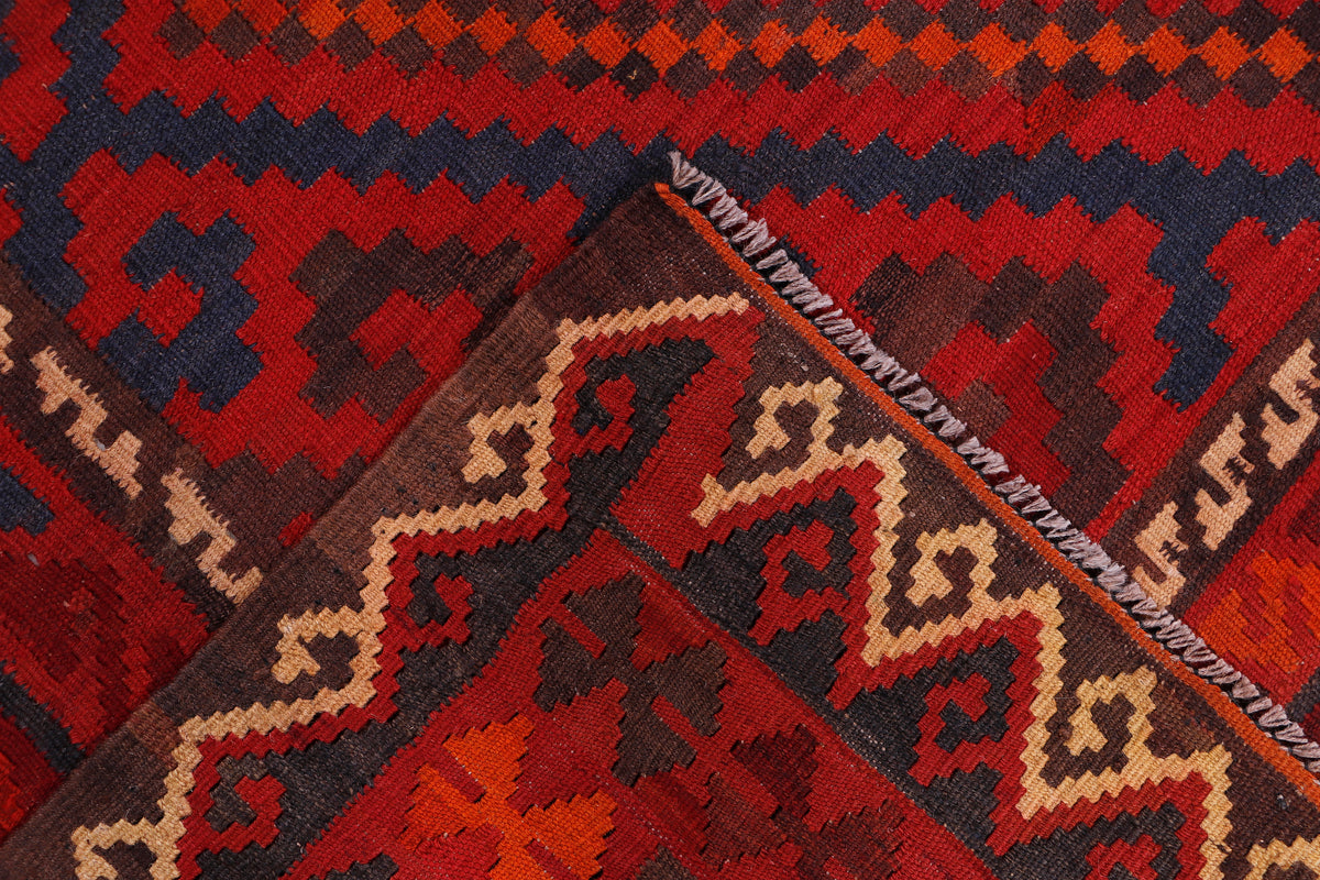 Red kilim rug with curved patterned medallion and dark geometric border.