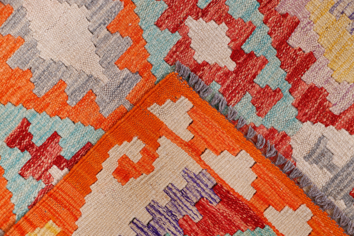 Kilim rug close-up with orange, red, and gray geometric diamond and cross patterns