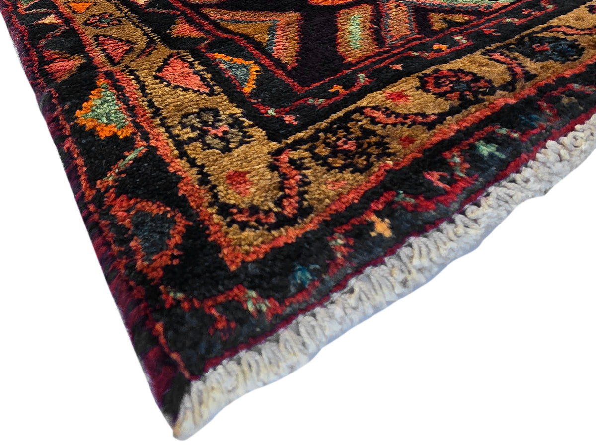 Hamedan rug corner with fringe trim and bold geometric pattern in dark navy