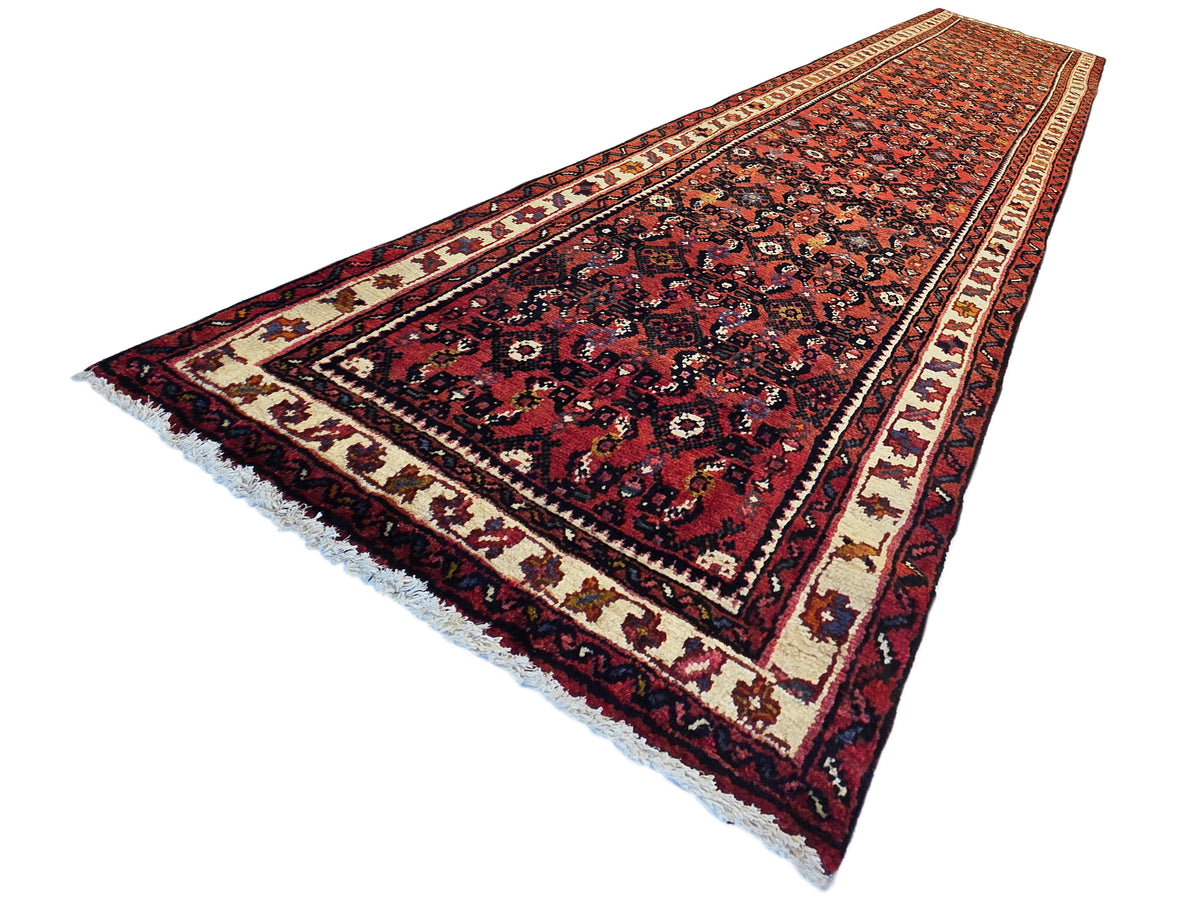 Burgundy runner rug with navy and cream geometric motifs and fringed edge