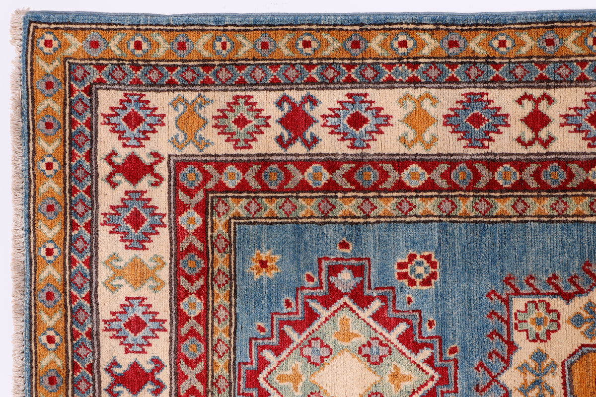 Blue rug with red and cream floral corner details and patterned border