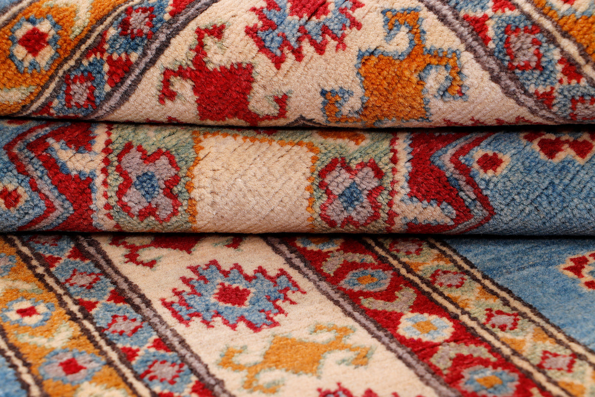 Rolled edge of blue patterned rug with red and cream motifs