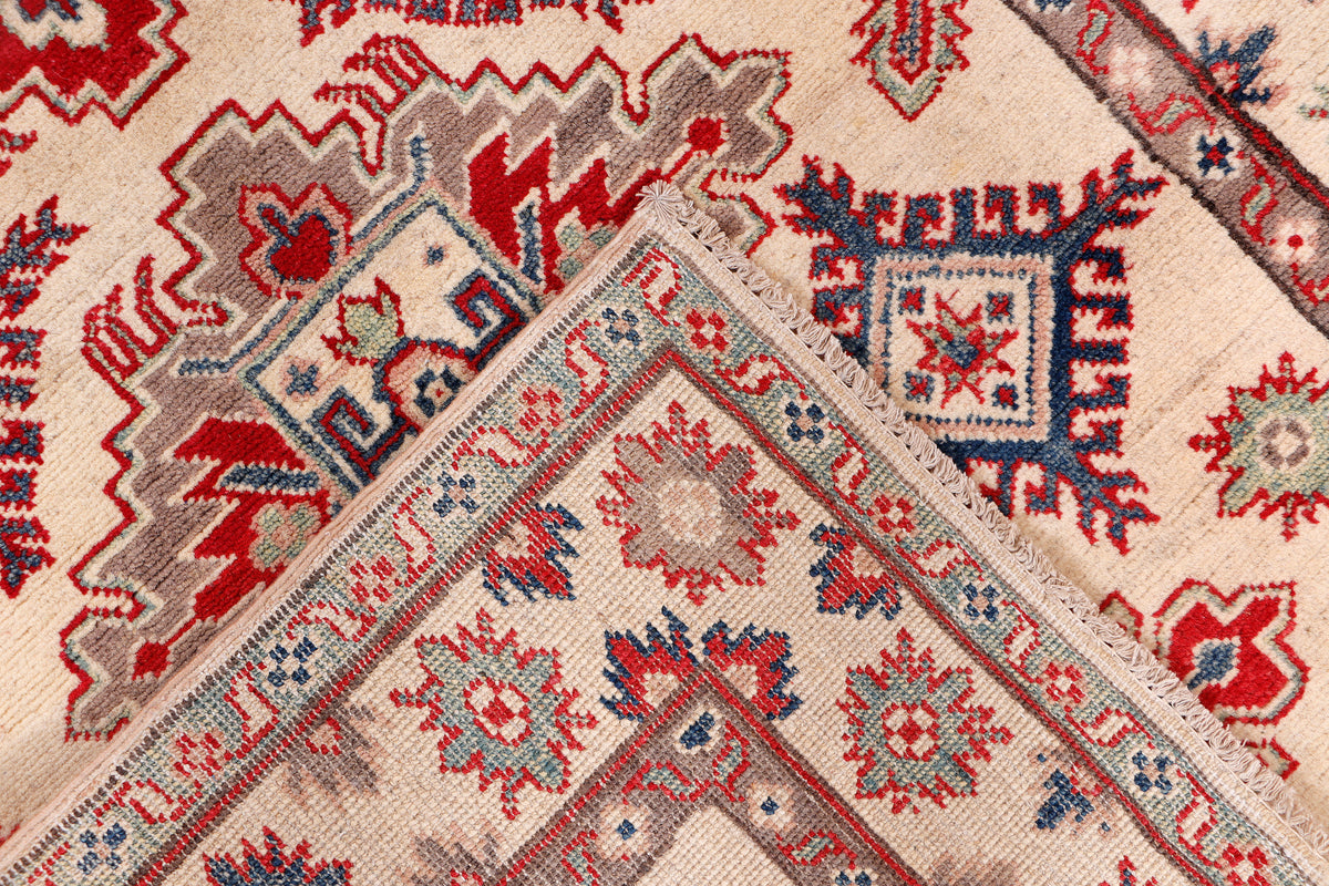 Kazak red rug close-up with small geometric stars and border stripe detailing