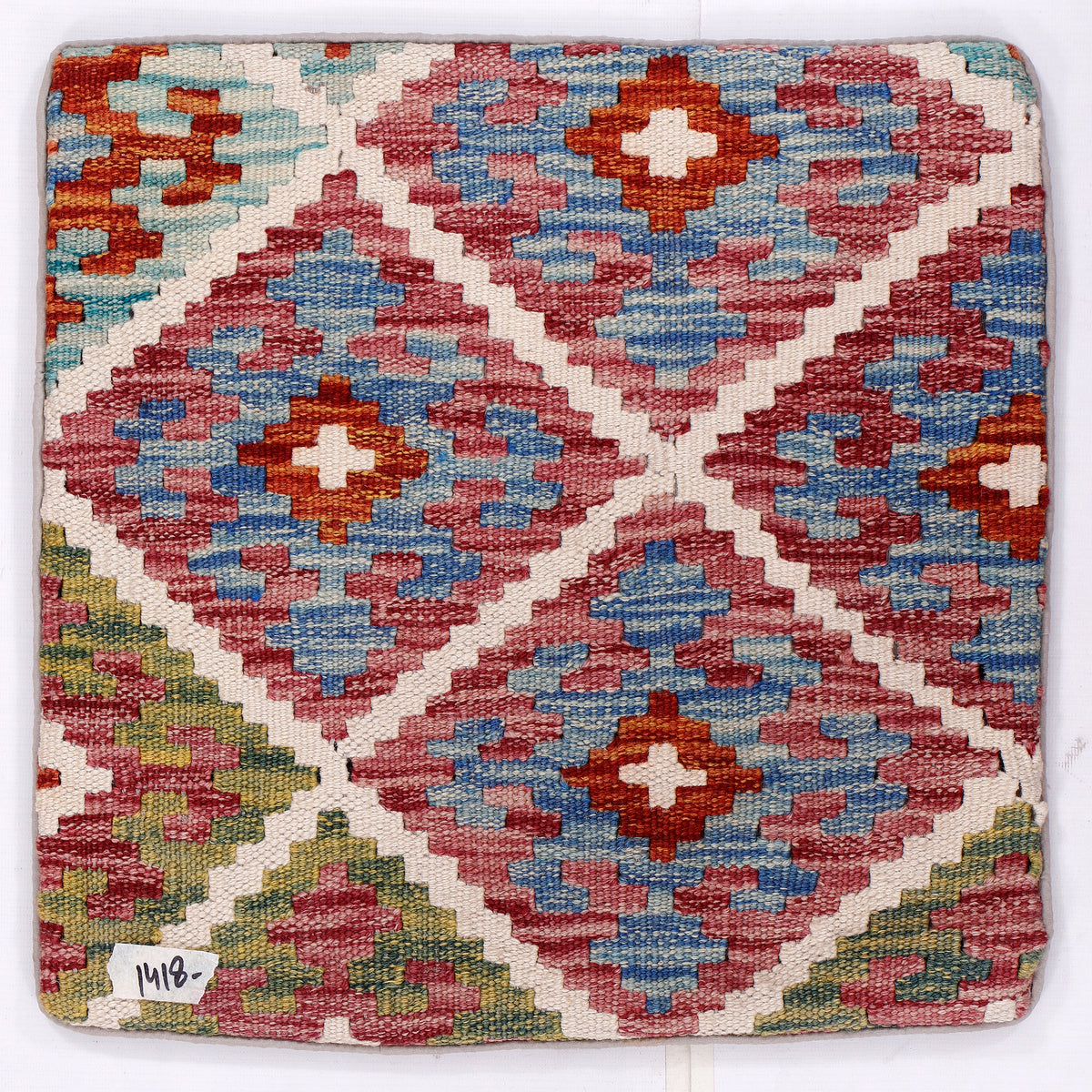Square kilim cushion cover closeup with blue, red, and cream diamond motifs
