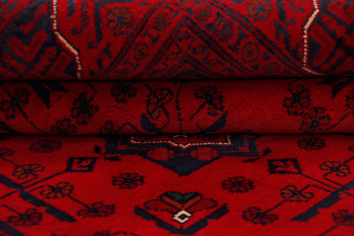 Red rug surface close-up with small floral motifs and dark ornamental bands