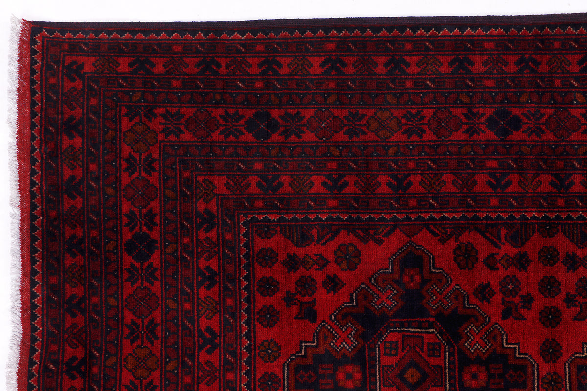Close-up of dark background red medallions and geometric border on rug corner