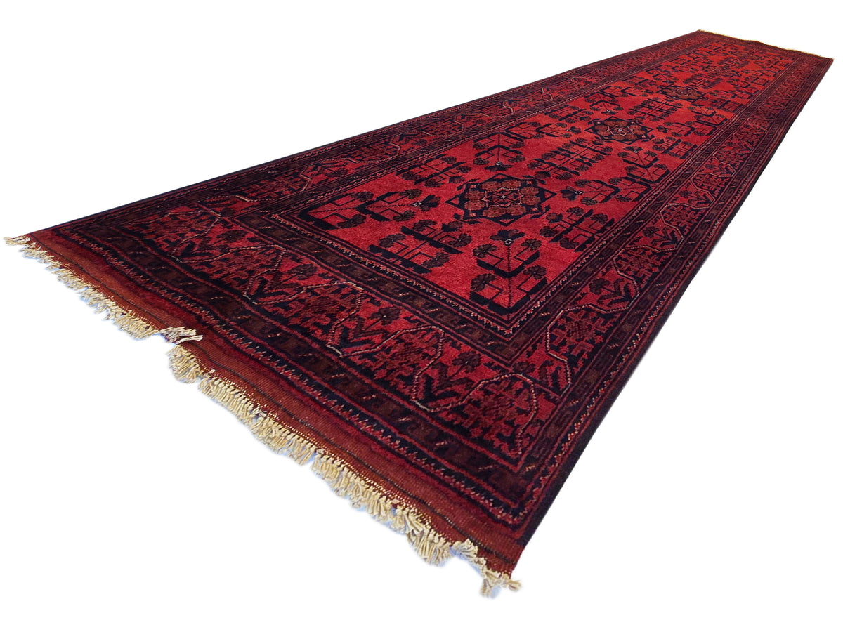 Khanmohamad rug runner in deep red with dark patterns and light cream fringe on ends.