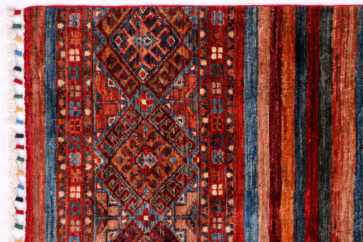 Geometric rug with central diamond medallion, red and blue field, fringe at left
