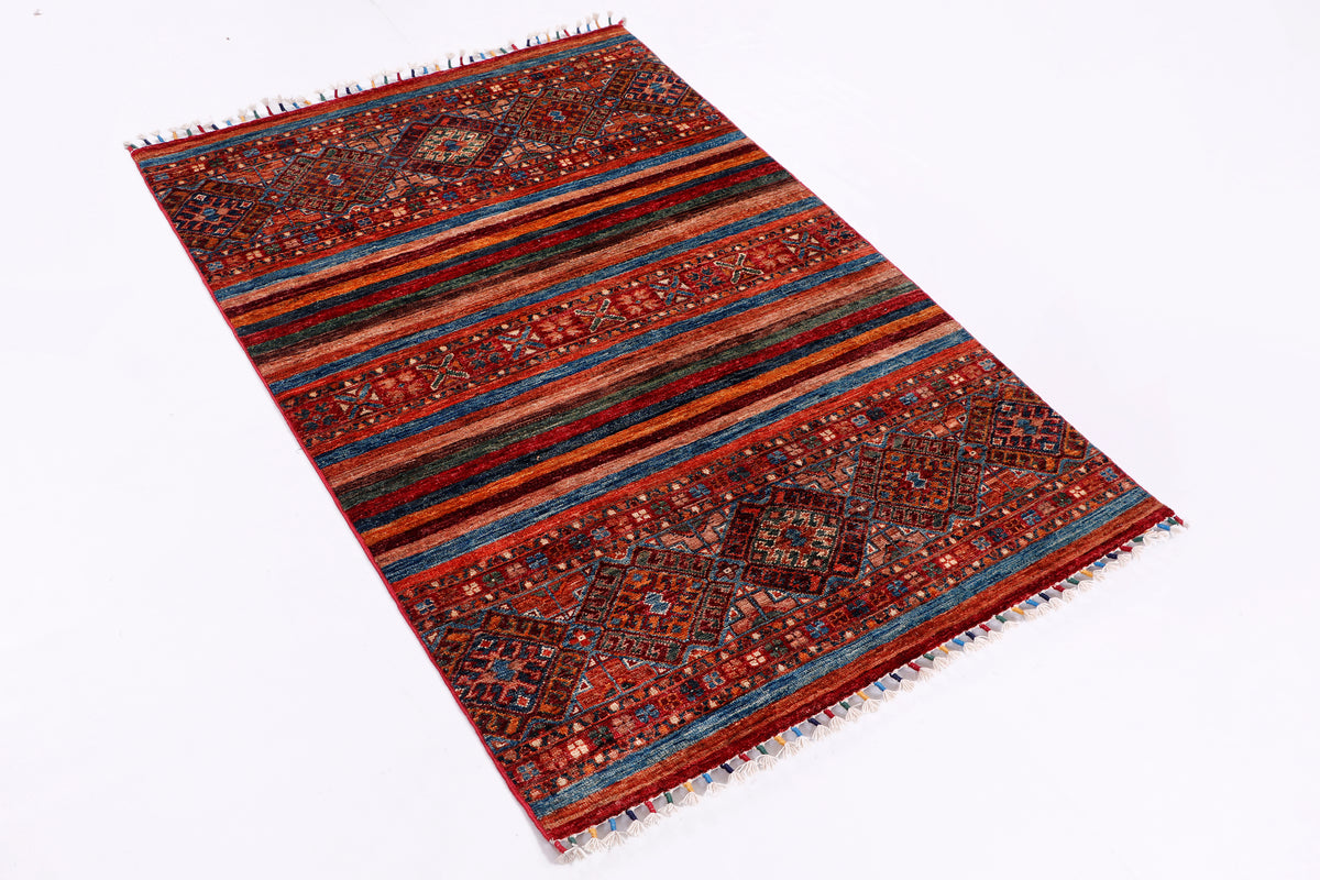 Red multicolor area rug laid flat on a white background, fringed ends and geometric design