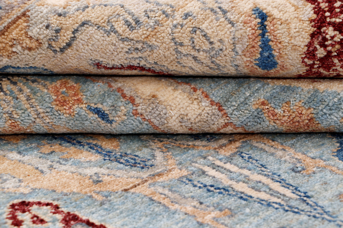 Khyber Oushak rug edge, rolled pile showing light blue, beige, and blue/red accents