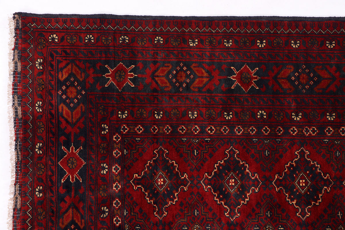 Red rug with dark navy border, central medallion, and repeating diamond motifs