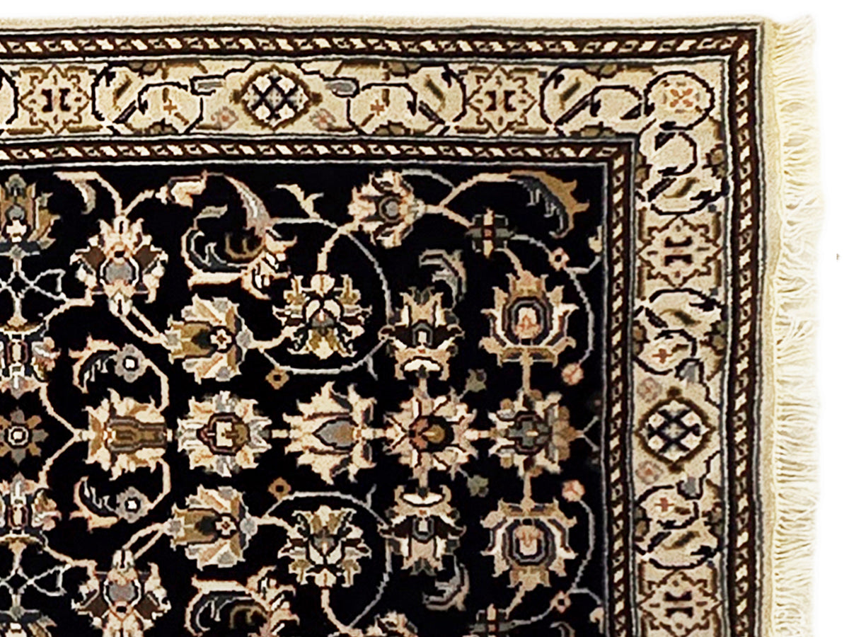 Close-up of runner rug pattern with black field, gold floral motifs, and cream border