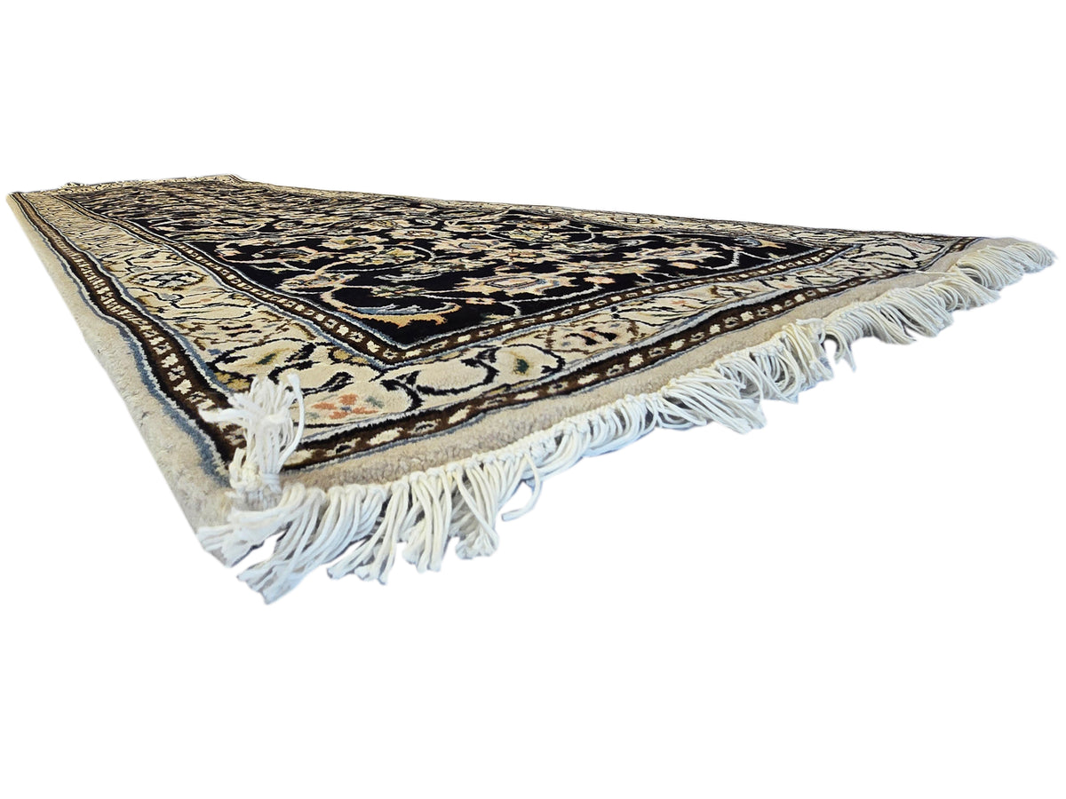 Runner rug with light cream backing tone at edge; black and gold design with fringe