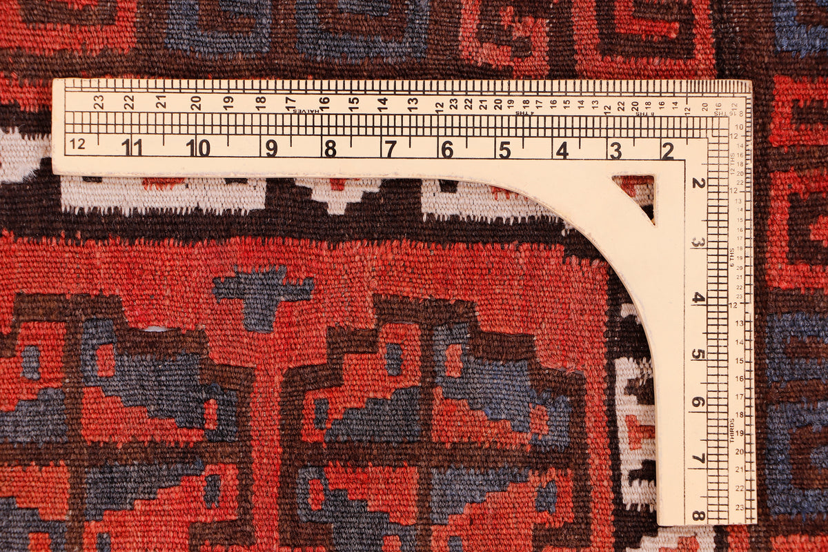 Kilim rug border detail with measuring tape, red and dark blue geometric design