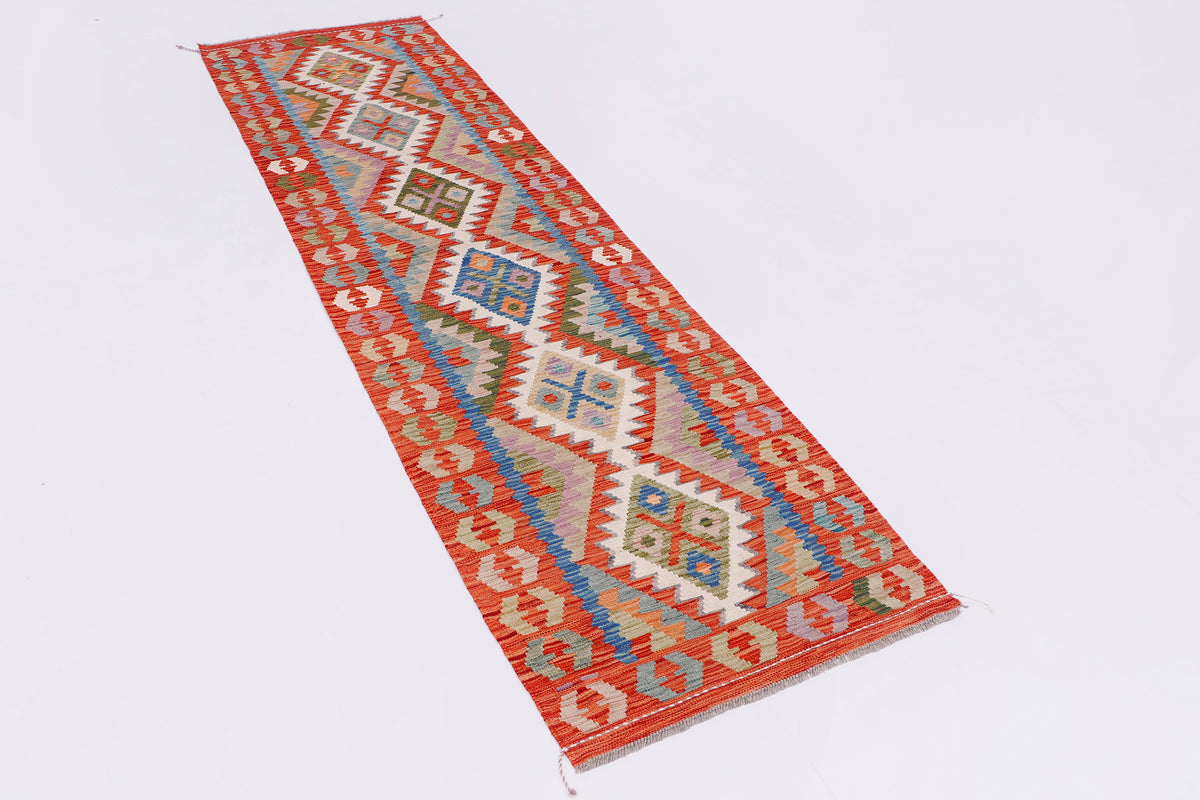 Rectangular kilim rug with red edge, white field, and multicolor chevron diamond pattern
