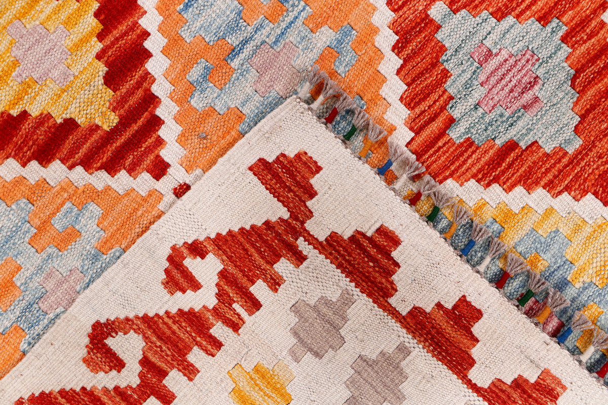 Multicolor kilim rug with geometric diamonds and border, close-up view.