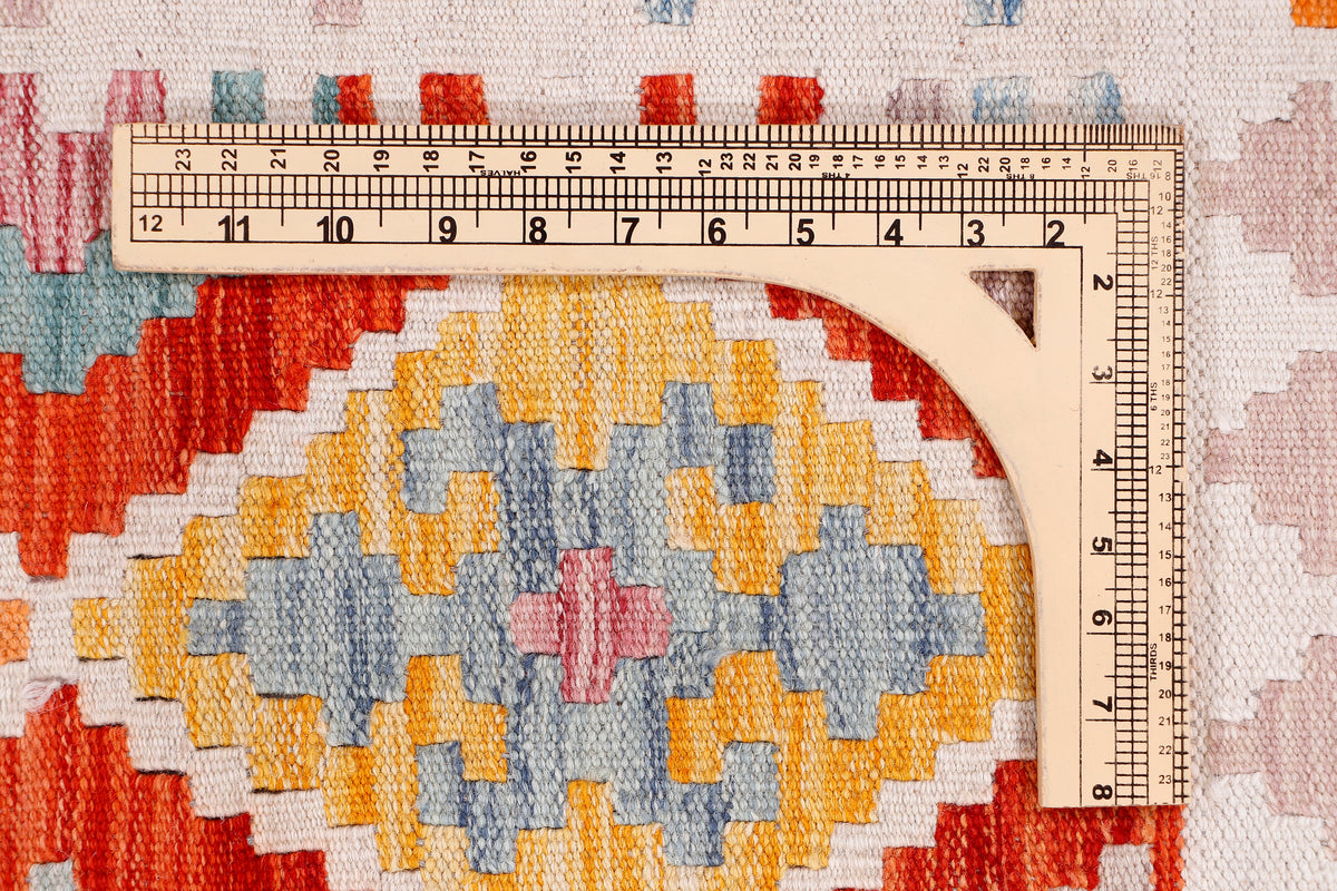 Kilim rug with geometric pattern and measuring ruler for size, top view detail.