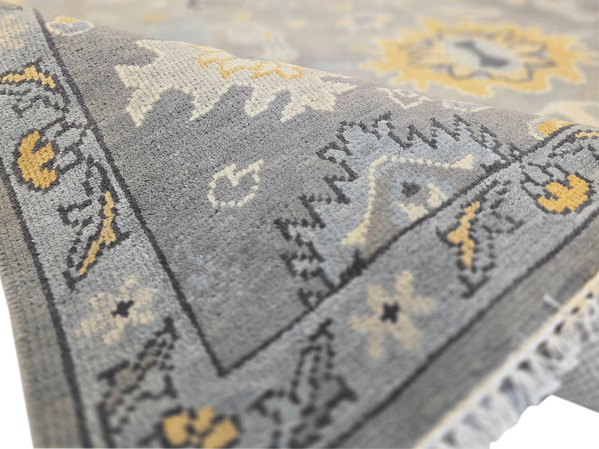 Oushak rug detail showing gray pile texture with yellow and dark pattern accents.