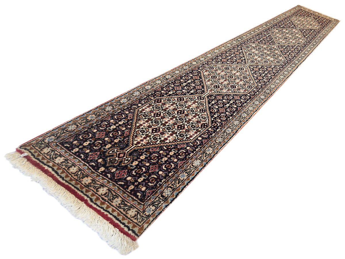 Navy and red patterned runner rug with central medallion and short fringed ends