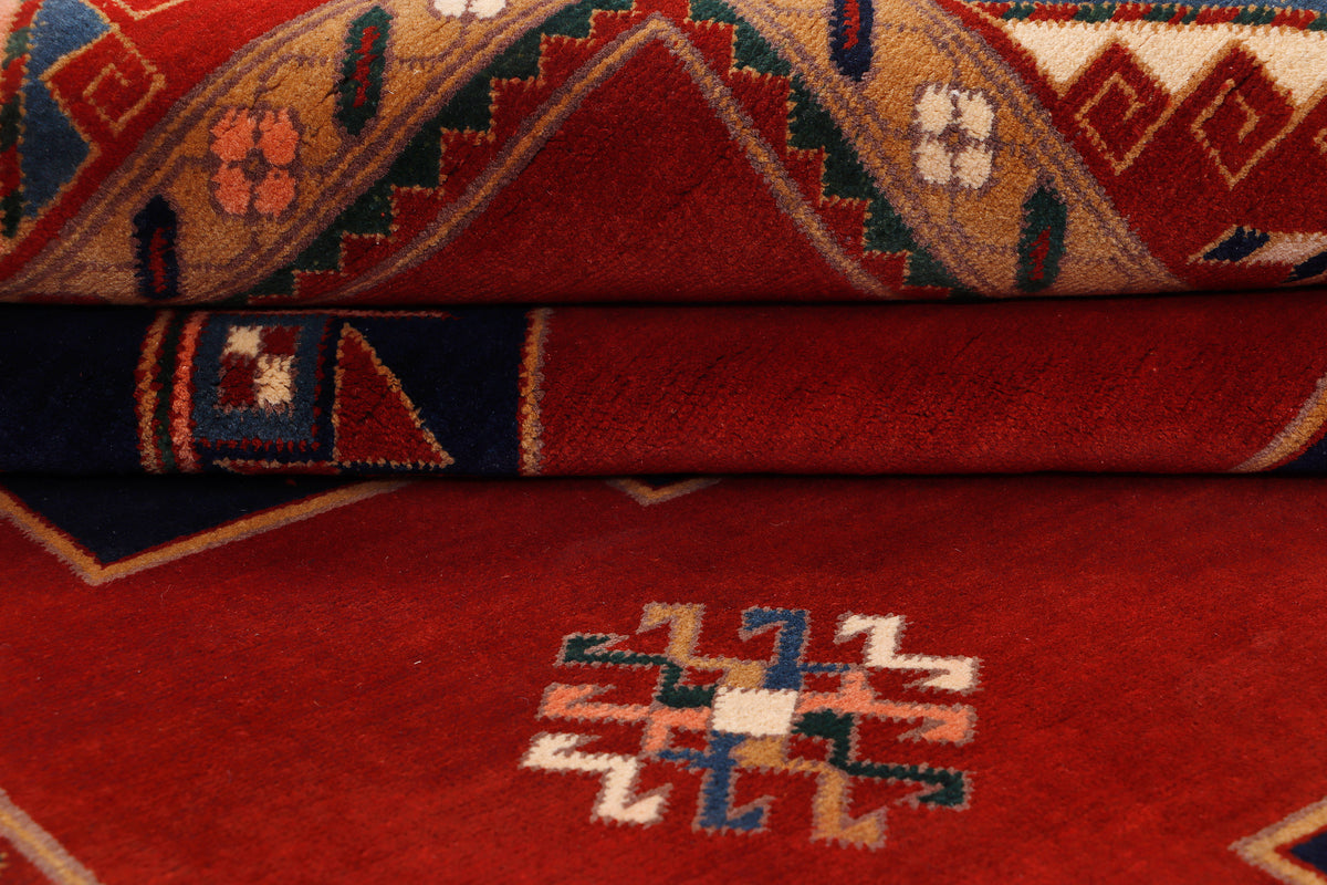 Folded red rug showing geometric stripe pattern and central zigzag motif