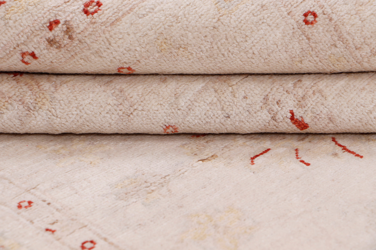 Beige rug pile close-up with red speckled motifs and folded edge