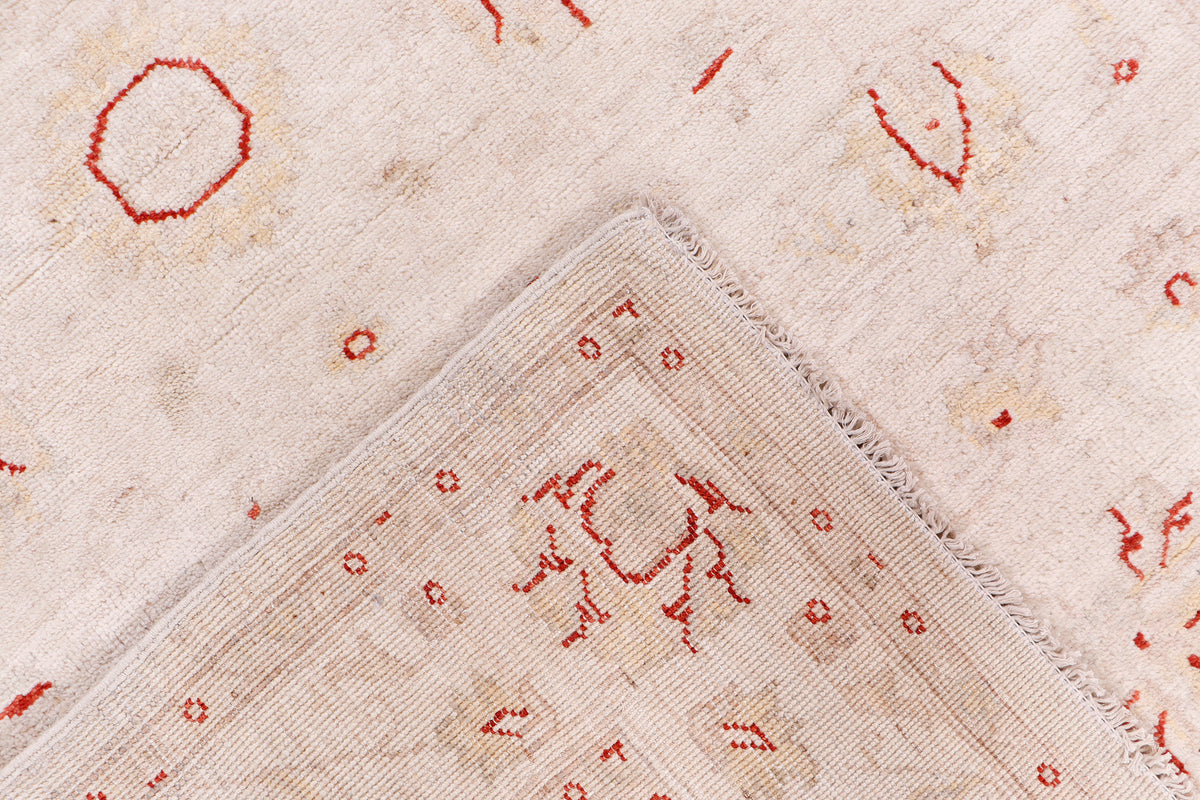 Beige rug close-up showing red motifs and thin patterned border seam