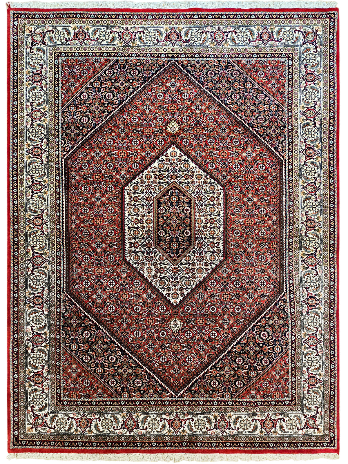 Ornate red and cream rug with diamond medallion, navy accents, and fringed edge
