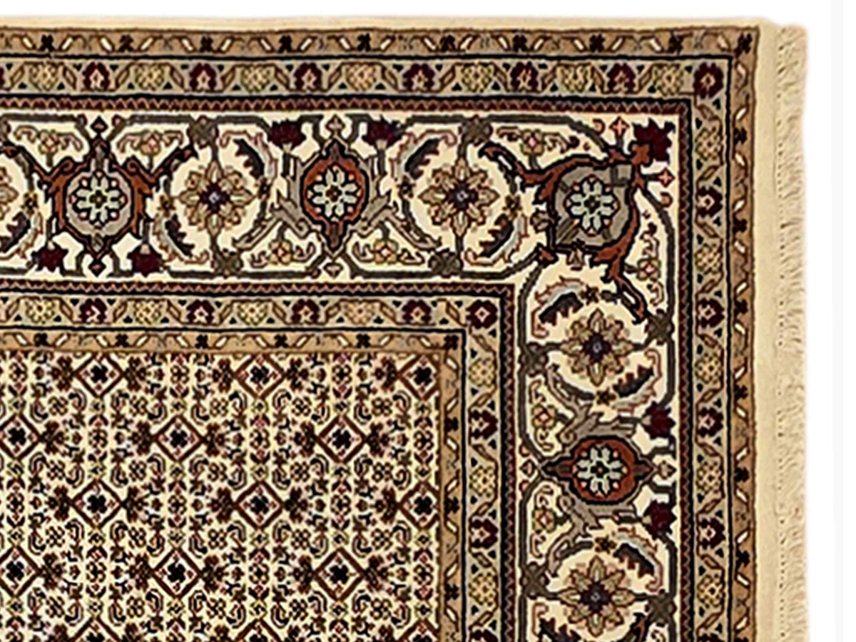 Ornate beige rug detail with dark floral motifs and red accents along border