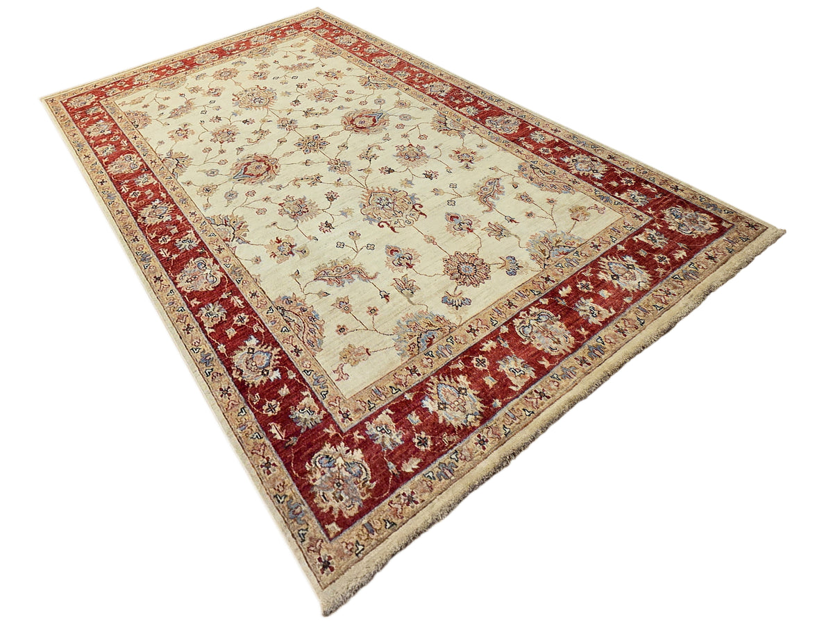 Cream rectangular rug with red border, central floral motif, and short fringe edges.