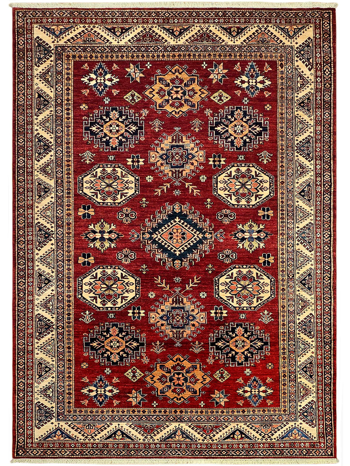 Red patterned area rug with cream border and geometric motifs, frayed edges