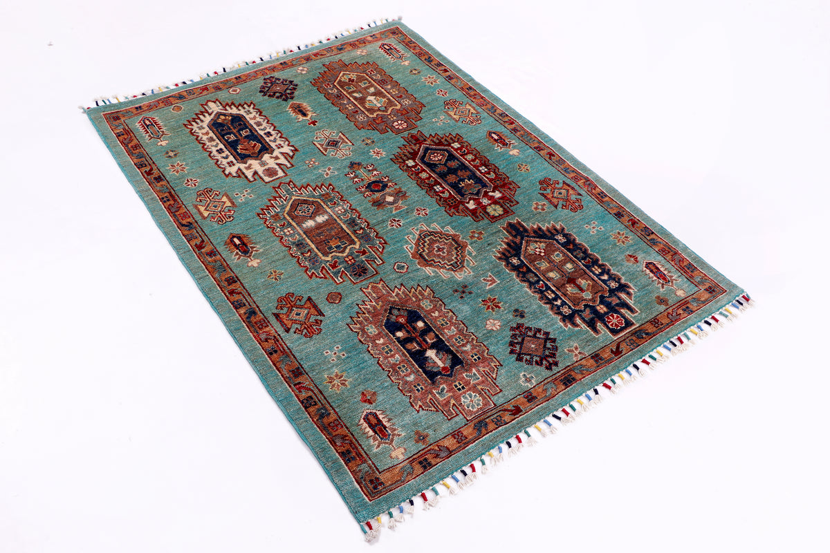 Turquoise rug with central medallions, red and navy geometric motifs, and fringed border