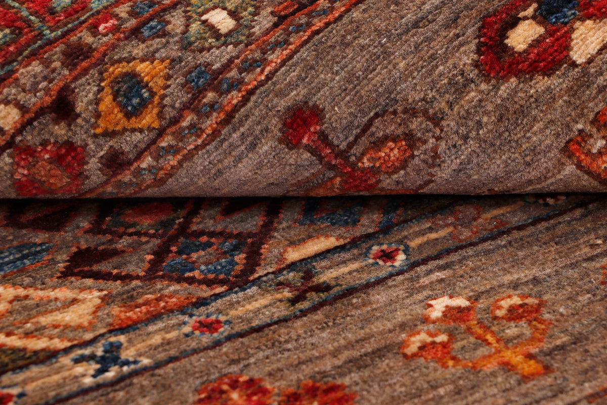 Grey rug close-up with geometric pattern in orange, blue, and rust tones.
