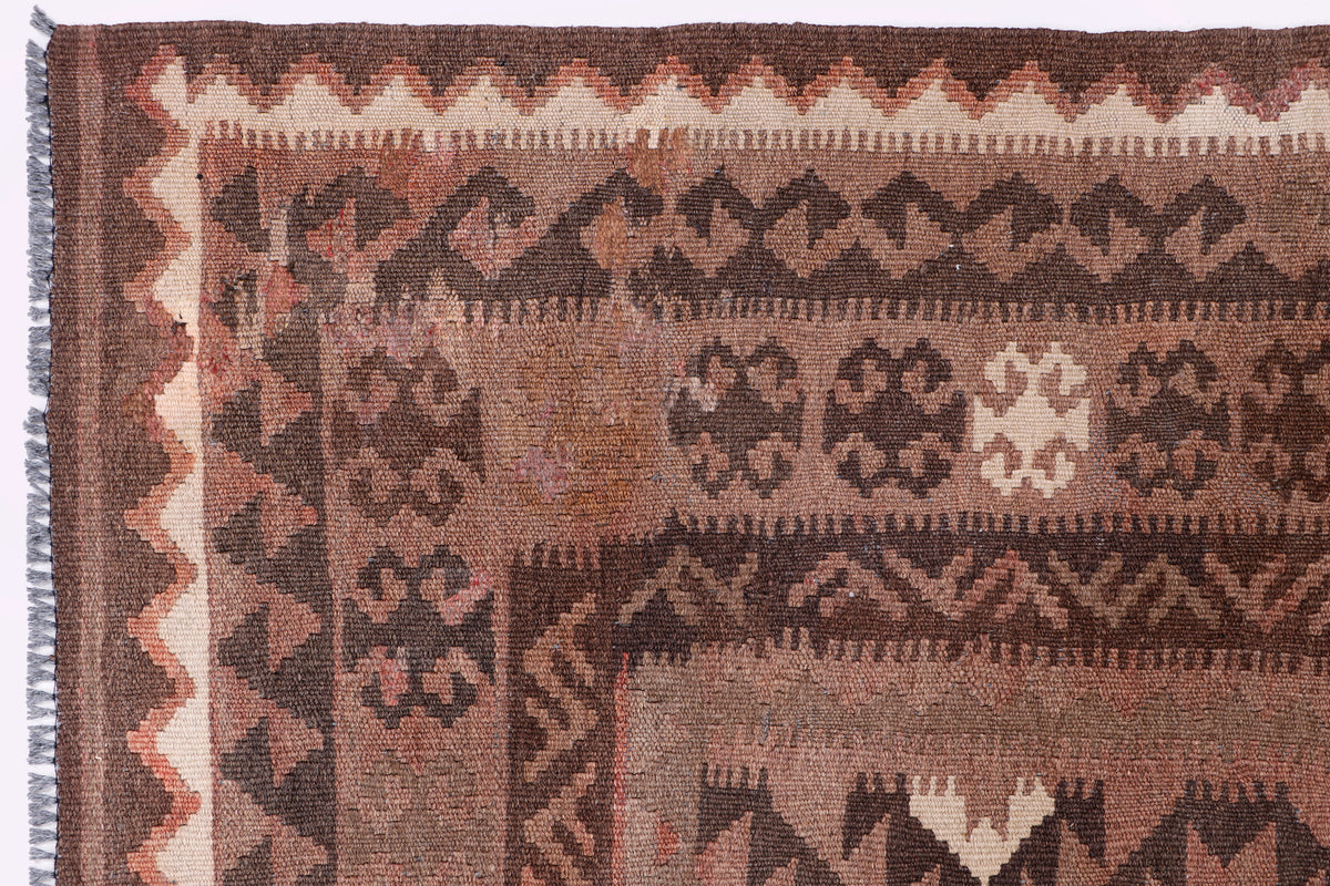 Close-up brown kilim rug with tribal medallion motifs and red geometric trim