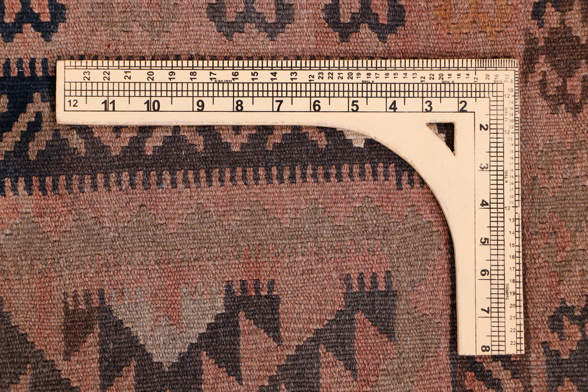 Brown kilim rug measuring detail with ruler along edge and geometric pattern