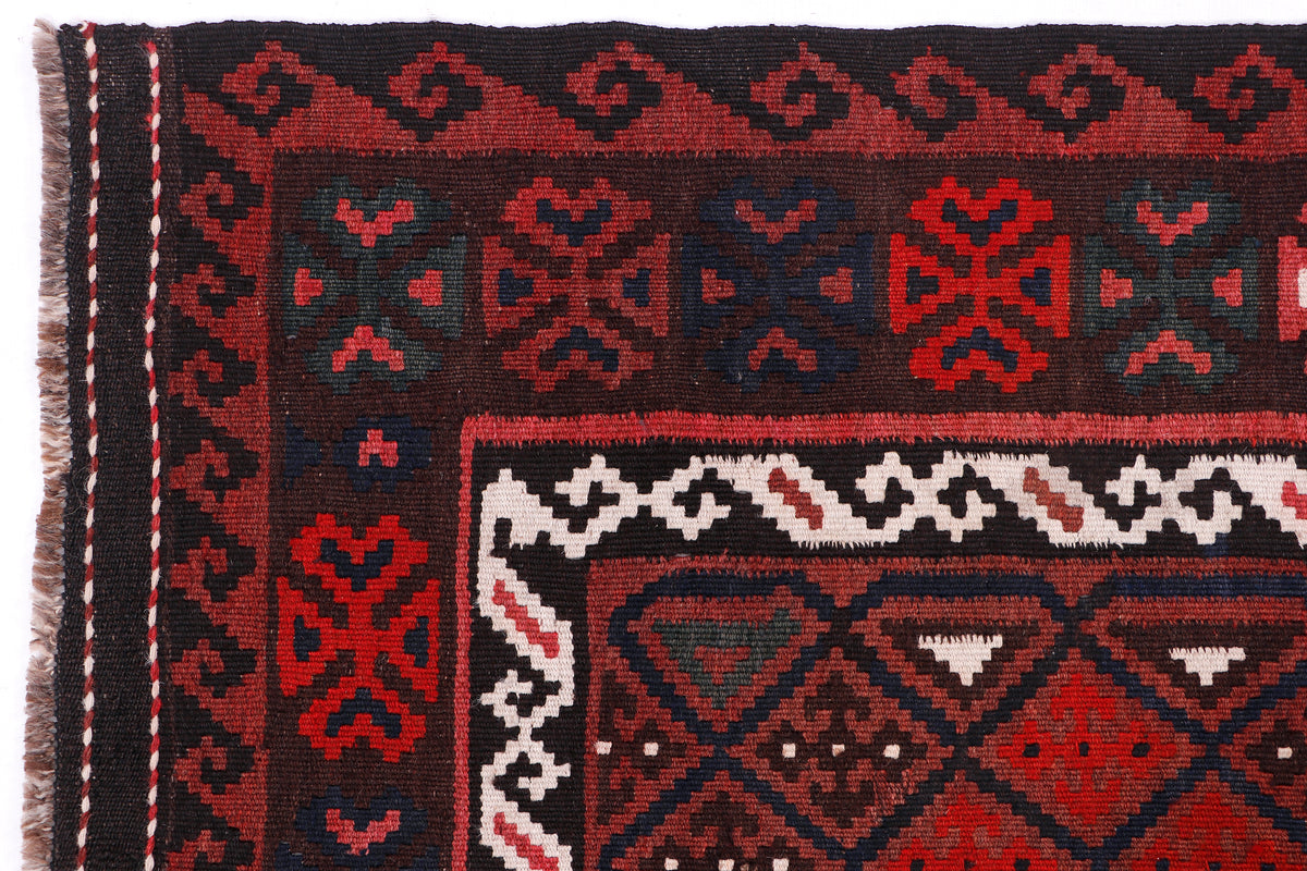 Close-up kilim rug corner with red, black, blue, and white geometric motifs