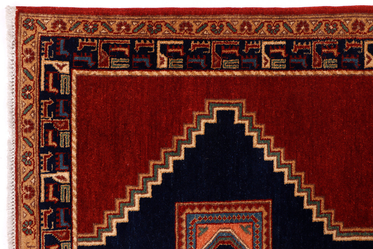 Red rug closeup with navy border and repeating geometric motifs