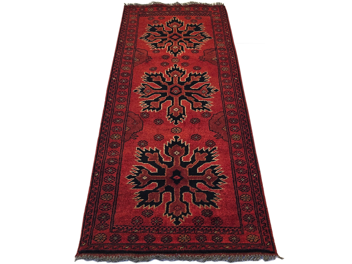 Red Afghan rug with central starburst motif, ornate border, and short fringe at ends.