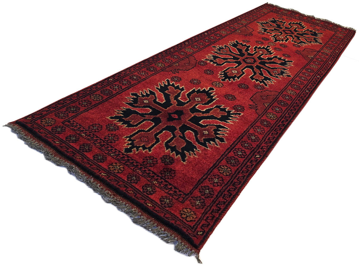 Red Afghan rug with geometric medallion and border, fringed edges, 145x55 cm.
