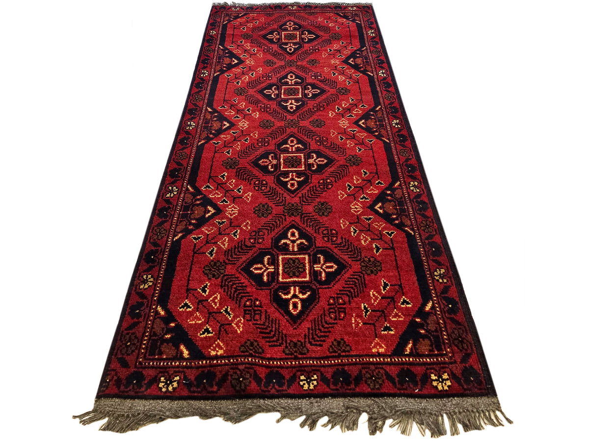 Red patterned Afghan-style runner rug with geometric medallions and fringed ends