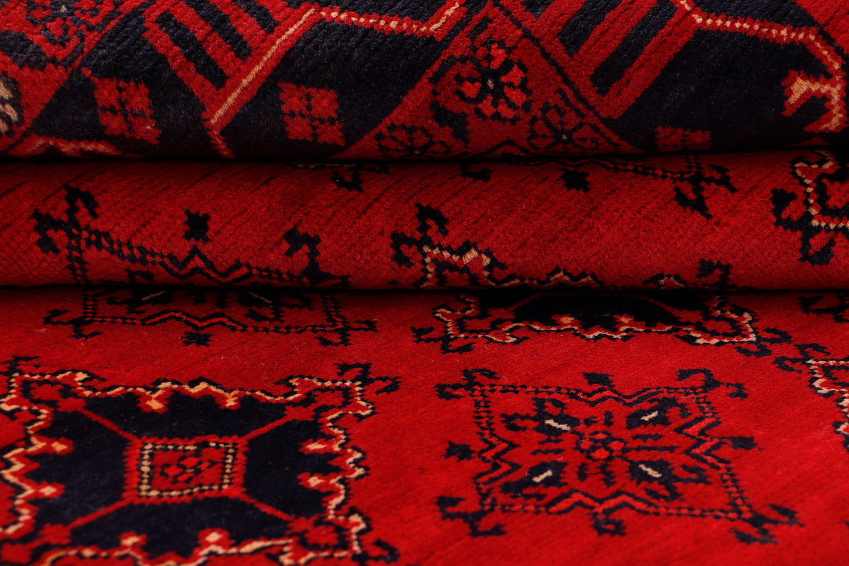 Red rug showing folded section with low-pile texture and ornate geometric patterns