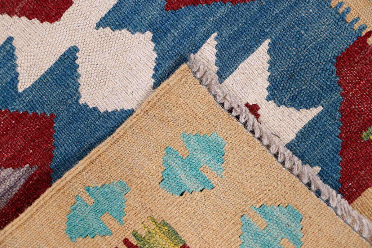 Kilim runner rug corner detail with frayed edge and blue tan red geometric pattern